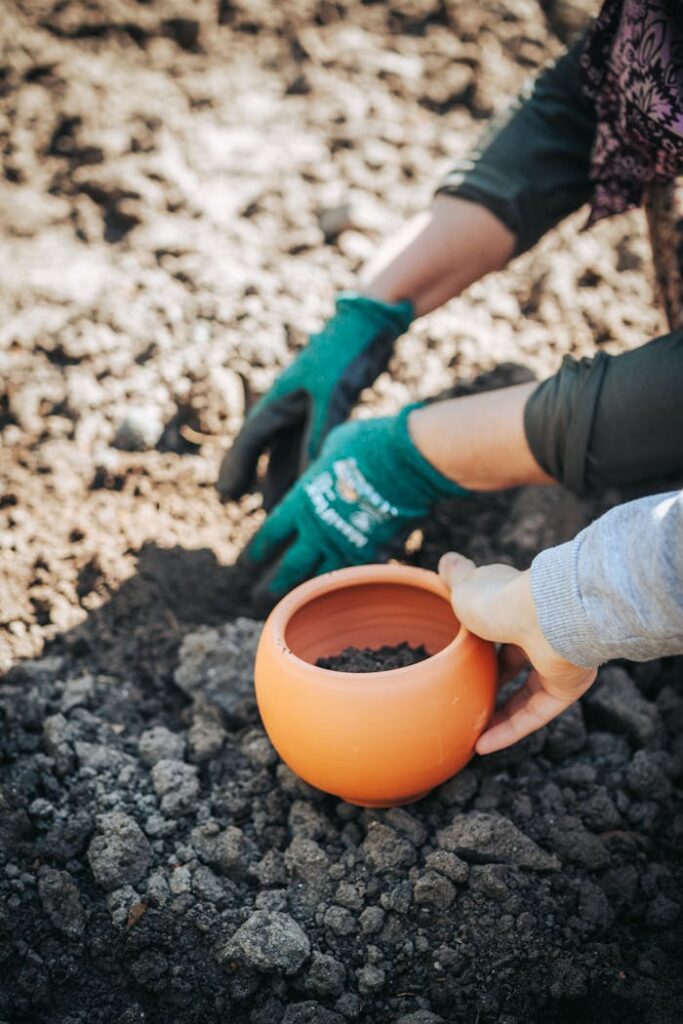 Close-up of hands planting soil in a terracotta pot, ideal for gardening themes.